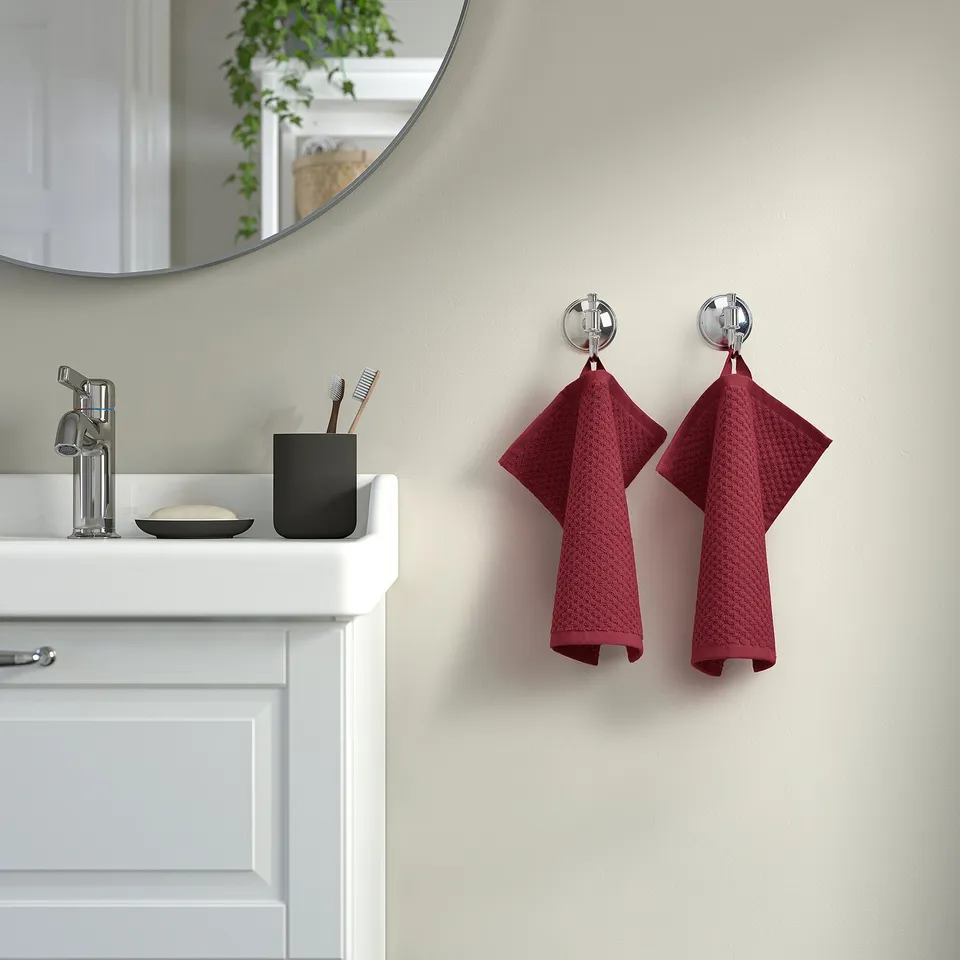 Maroon GULVIAL towel on wall hooks in bathroom.