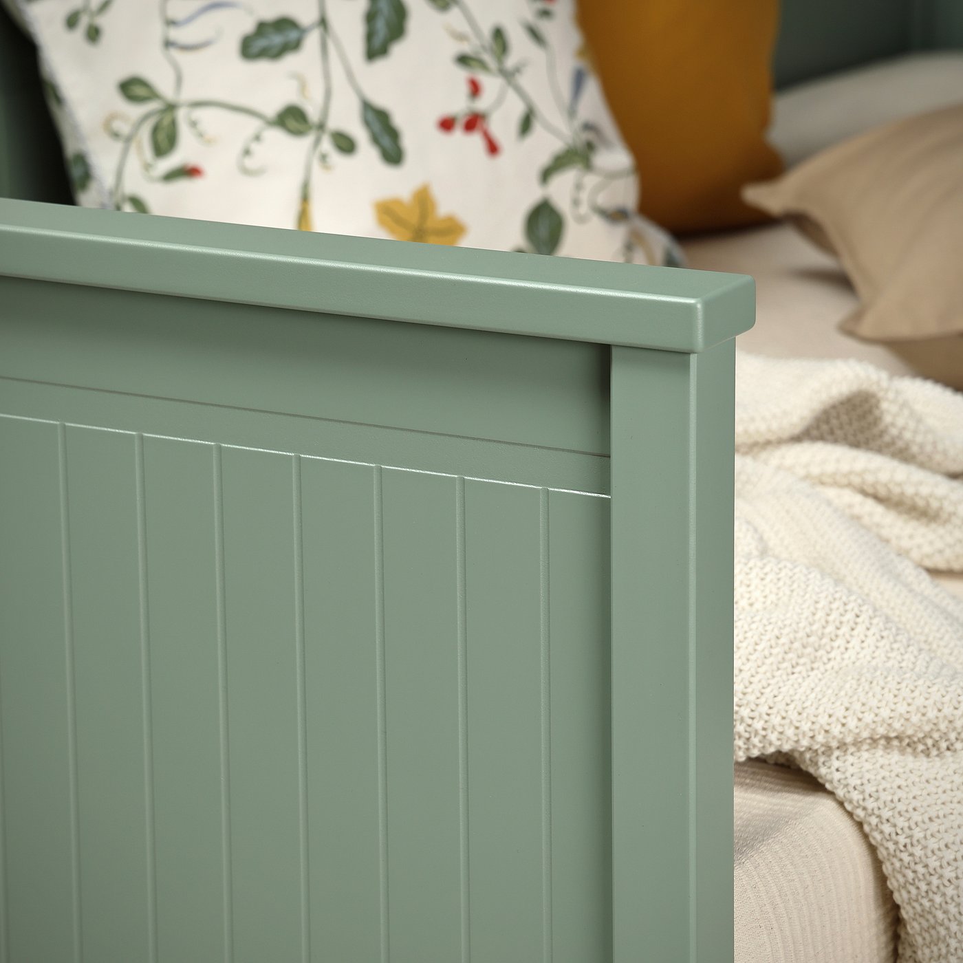 Close-up of green wooden headboard. Smooth, well-crafted edges, showing quality craftsmanship.