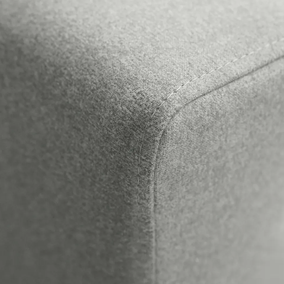 A close-up of a high-quality armchair corner, showcasing fine stitching and plush fabric texture.