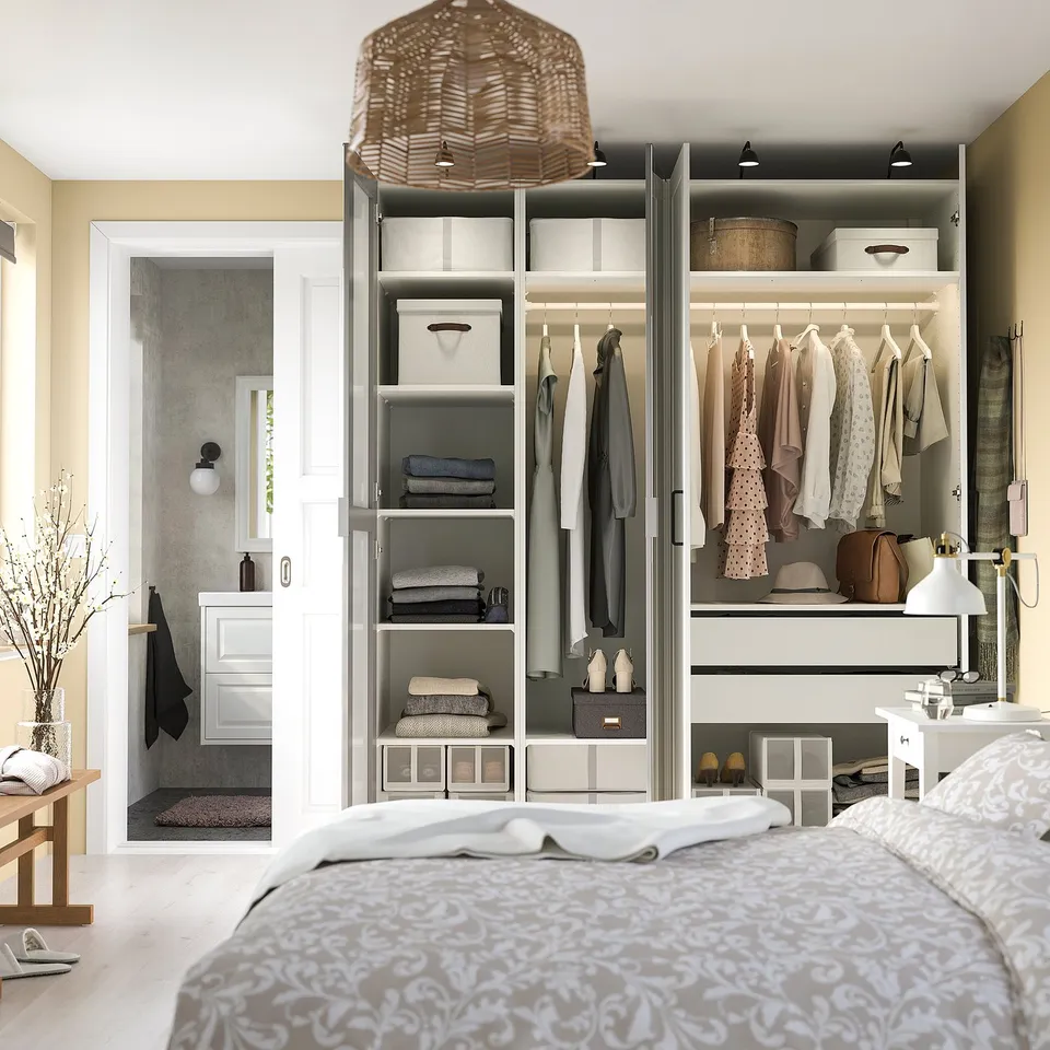 A PAX wardrobe with mirrored doors. Inside, it has shelves, hanging rails for clothes, and drawers with organisers. Theres also adjustable lighting.