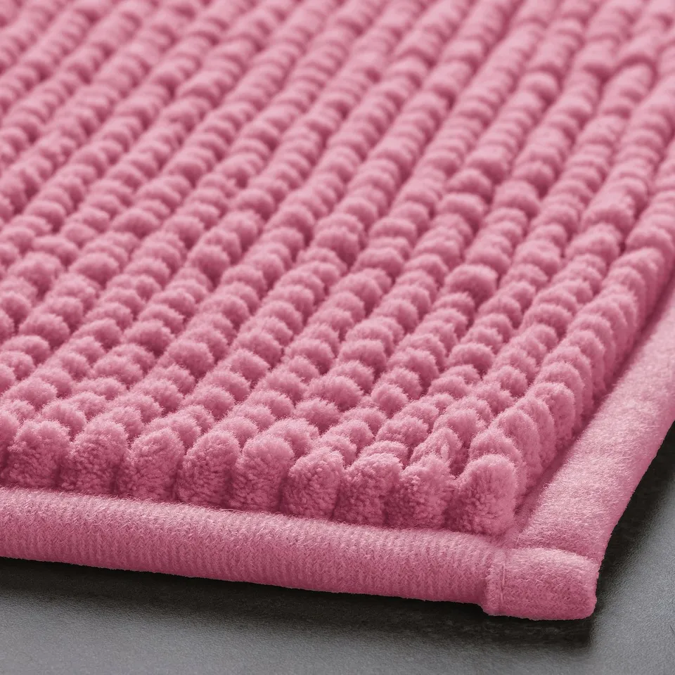 A close-up of a pink bath mat, showcasing its soft, textured surface and plush, inviting quality.