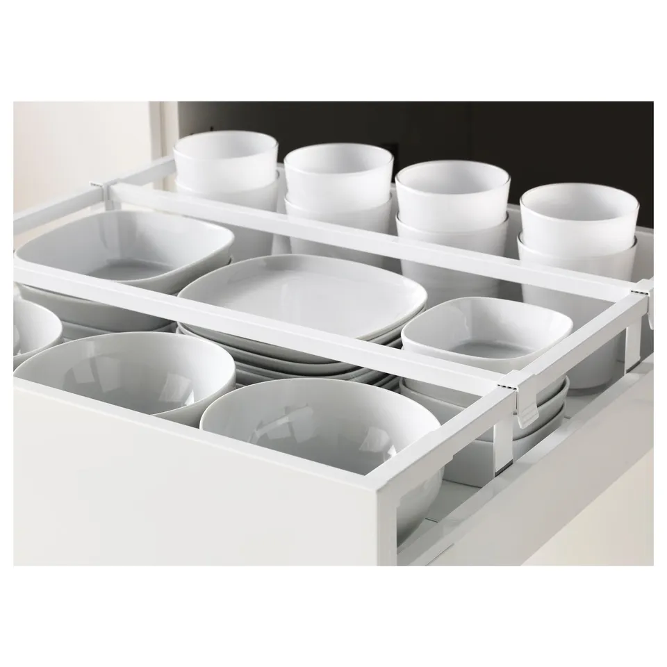 Kitchen drawer with multiple compartments holding white bowls and cups. Organised with adjustable dividers for efficient storage.