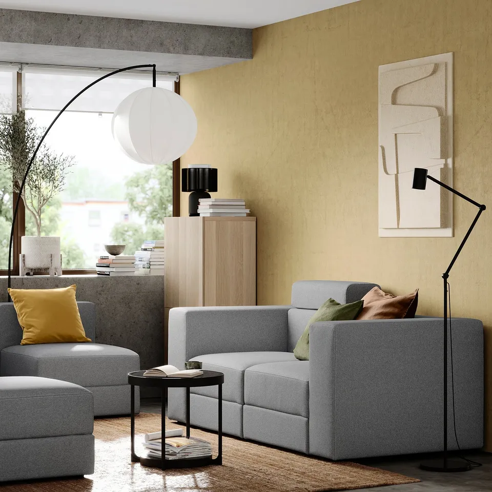 Grey JÄTTEBO modular sofa with side table, lamp, cabinet, art, and window view.
