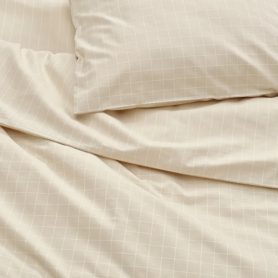Beige bedding with smooth texture, subtle stitching, and neat edges.