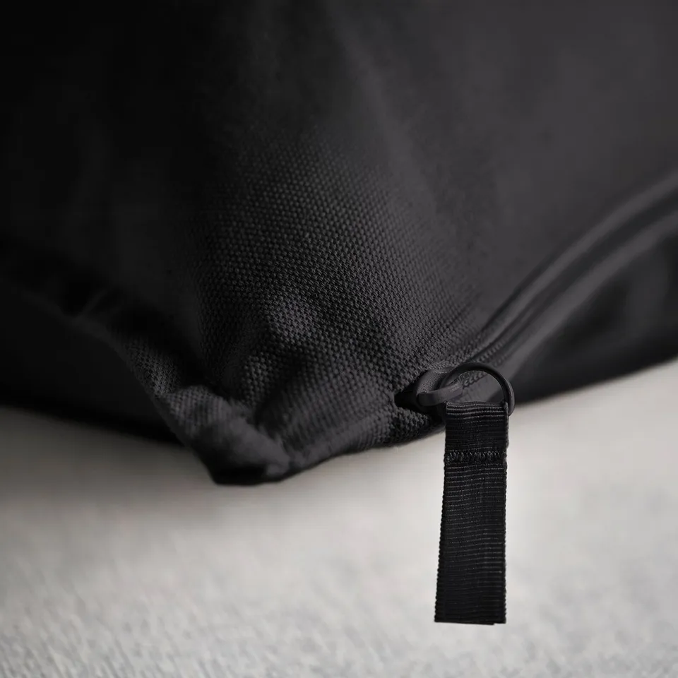 Black cushion cover with sturdy zip pull, made from textured fabric, showcasing quality and durability.