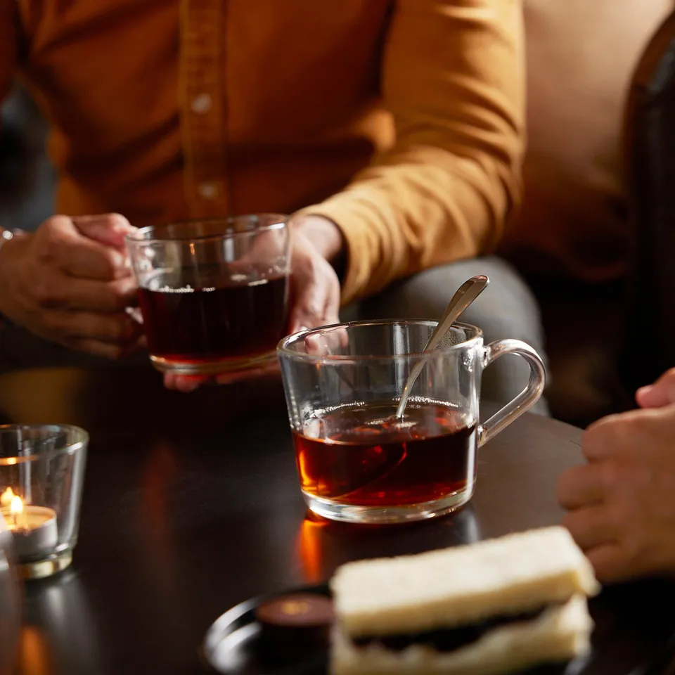 People with tea in clear mugs, showing strength, handles for easy hold.