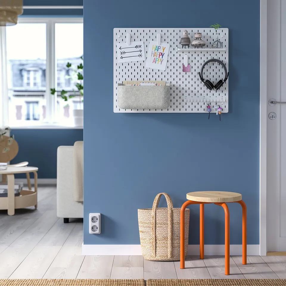 Blue room with SKÅDIS pegboard, headphones, notes, basket. Orange stool and small basket below.