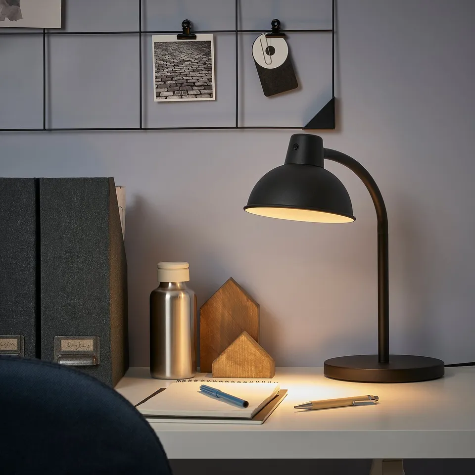 Minimalist black SKURUP lamp on desk with accessories.