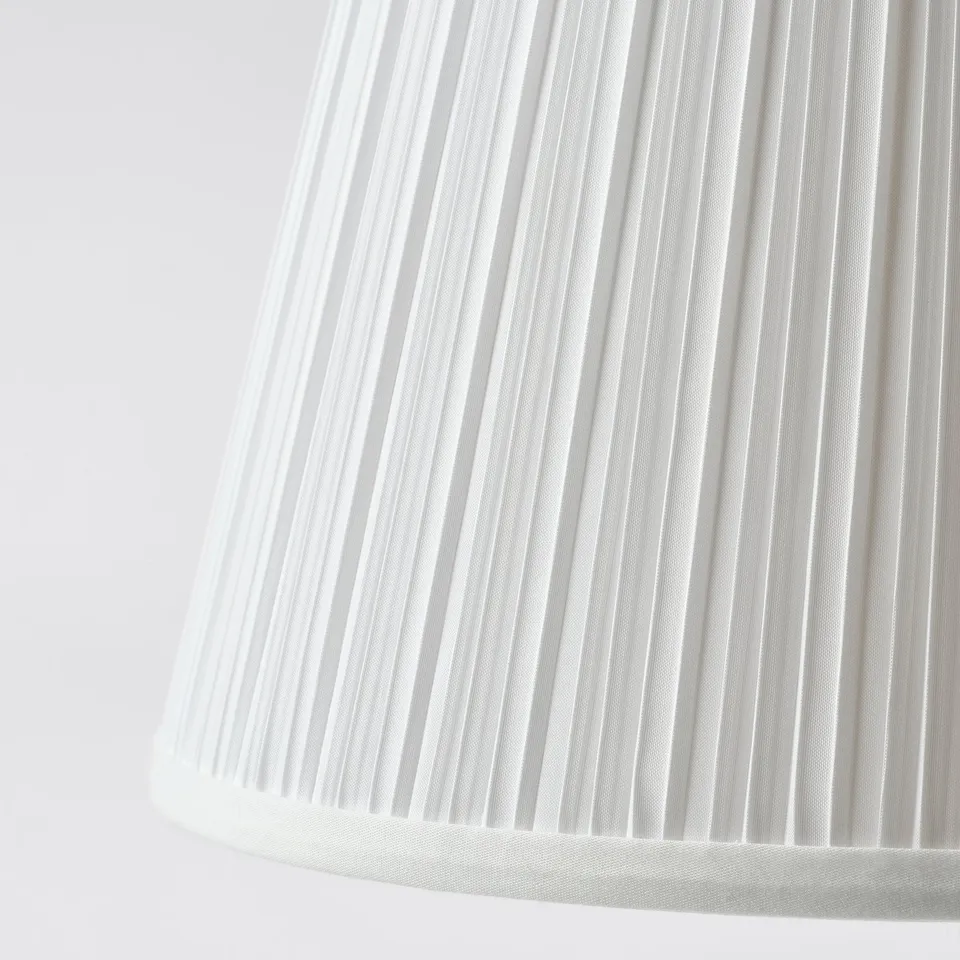 Close-up of a white pleated lamp shade, showcasing its smooth, evenly spaced folds.
