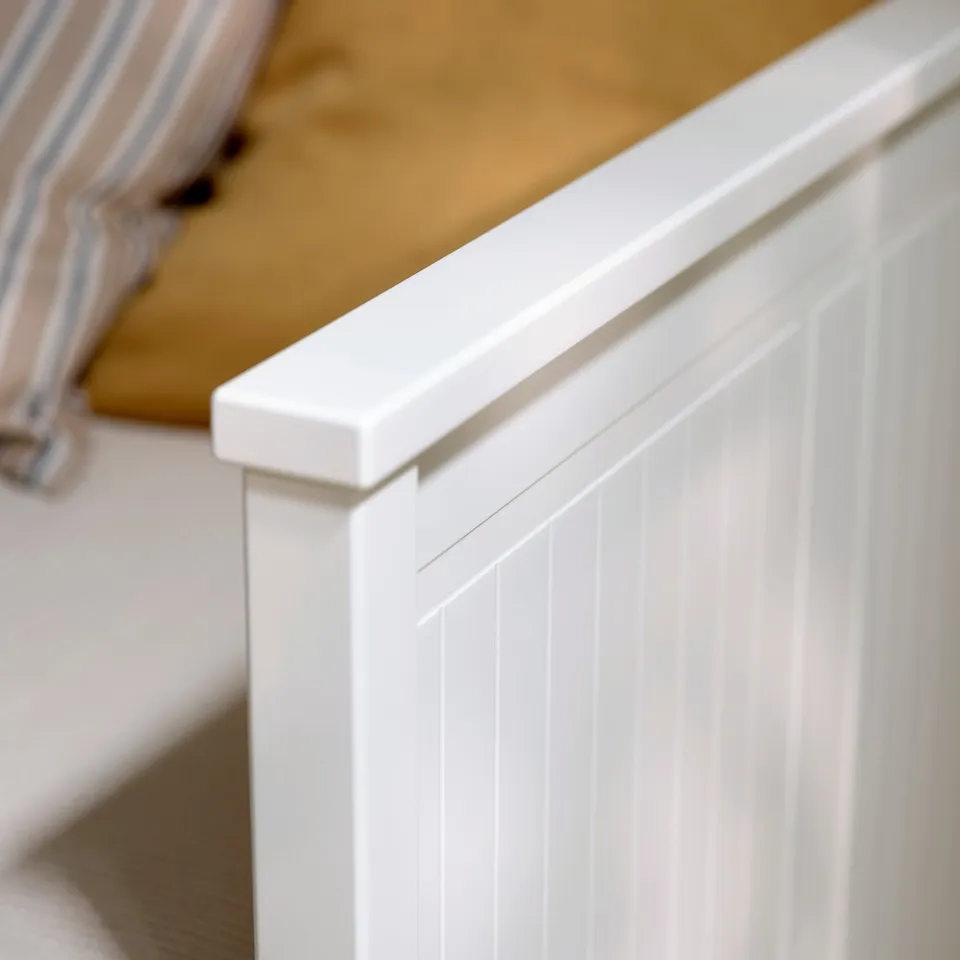 Clean, white wooden furniture with smooth, even finish, featuring vertical grooves, showing high-quality craftsmanship.