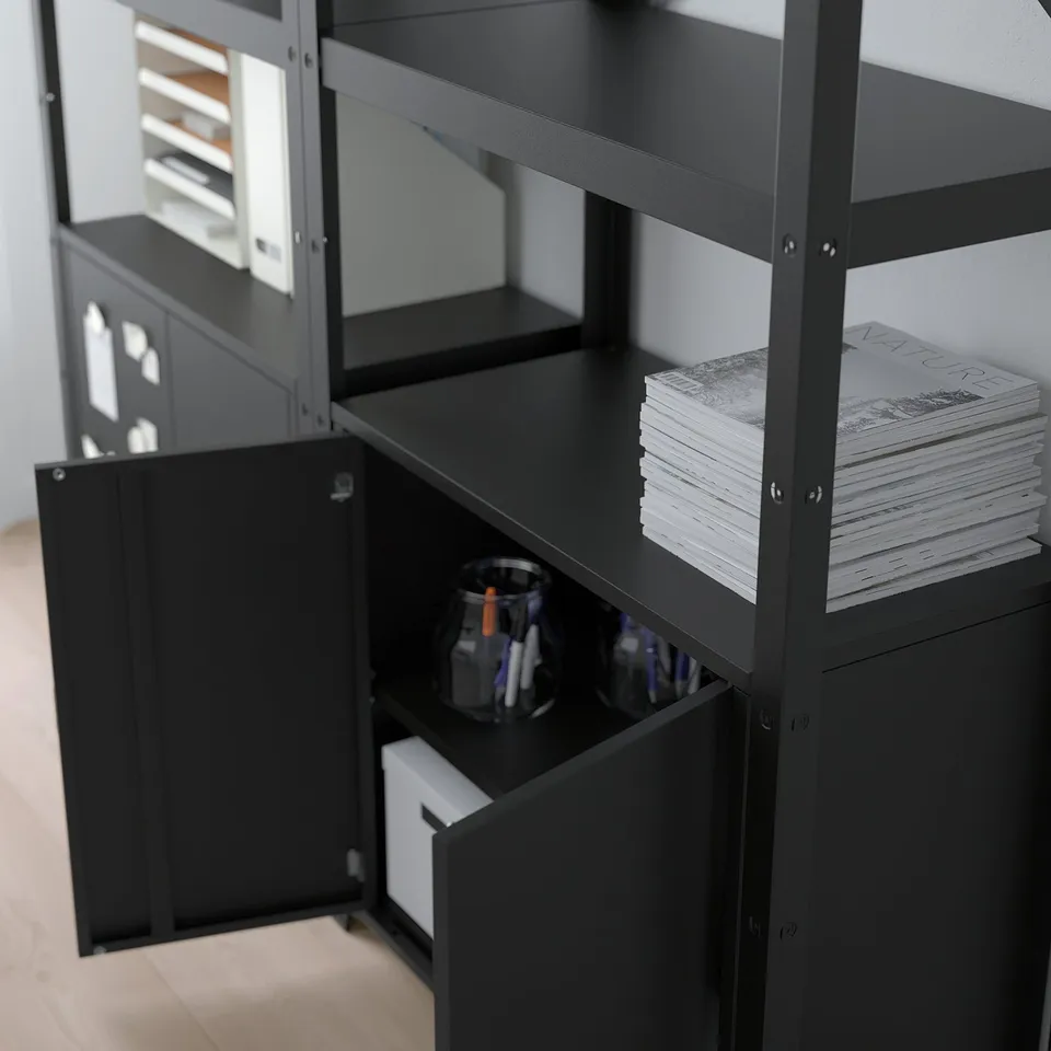 Black metal shelving unit with drawers, holding stack of magazines and a jar with pens, designed for heavy use and easy assembly.