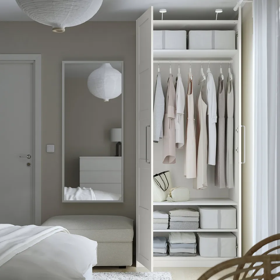 Modern bedroom with white PAX wardrobe, lights, mirror, bed, and pendant lamps.