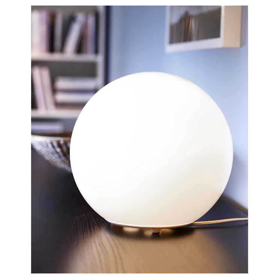 A FADO table lamp. It has a large, white spherical glass shade atop a simple, elegant base.