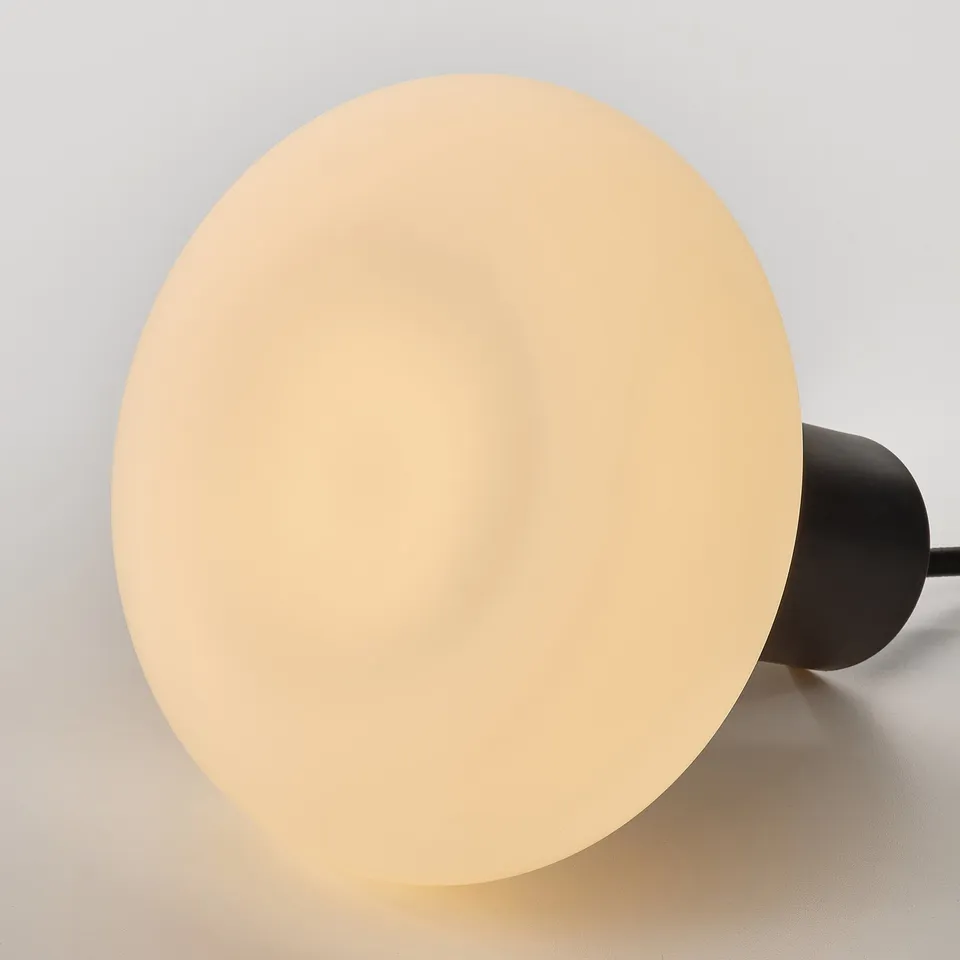 Small, round light with frosted glass, emitting warm, soft light. Simple & modern design.