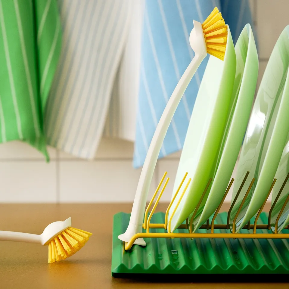 Yellow plate holder with green base, designed to dry plates upright, fits 9 plates, stored on counter or shelf.