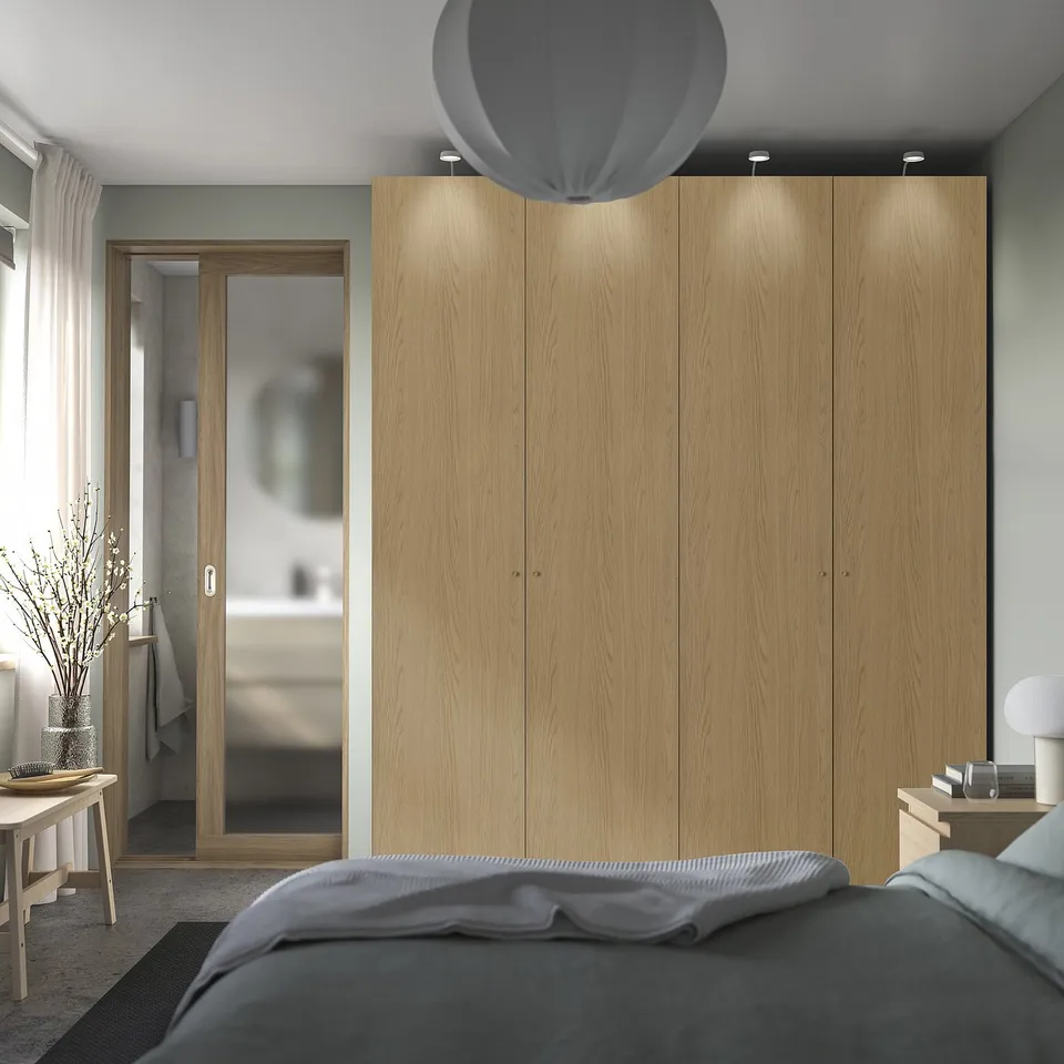Modern bedroom with large light oak PAX wardrobe, cosy bed, and natural decor.