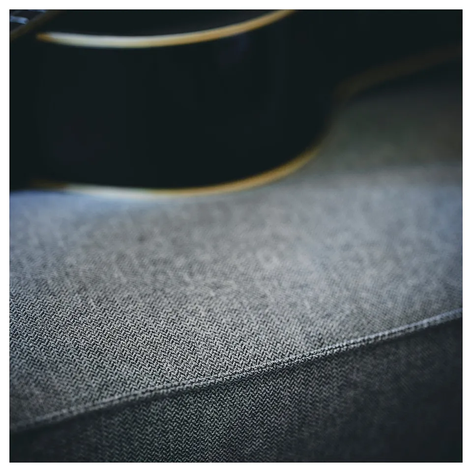 A black KIVIK sofa-bed with grey herringbone fabric, highlighting its smooth and cosy texture.