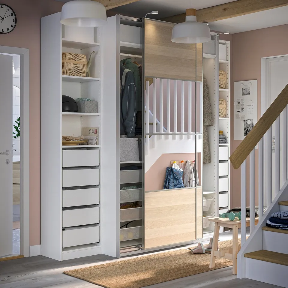 Modern white wardrobe with sliding doors, shelves, and drawers, featuring a built-in mirror and organised clothes and accessories.