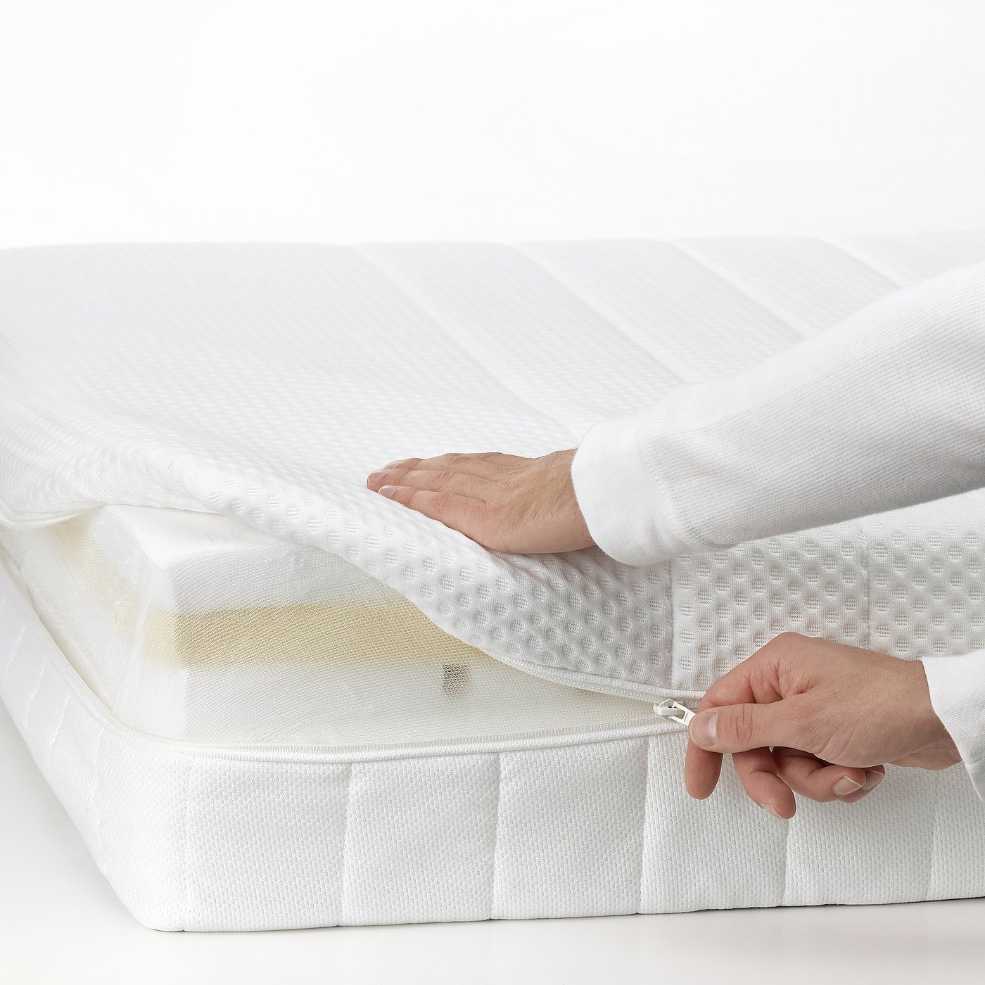 A person zips a protective mattress cover, ensuring hygiene and comfort.