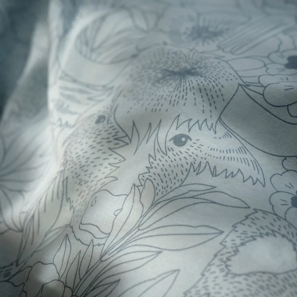 Floral pattern on soft fabric, likely bedding, with intricate blue lines and shapes. Close-up quality texture and detailed design.