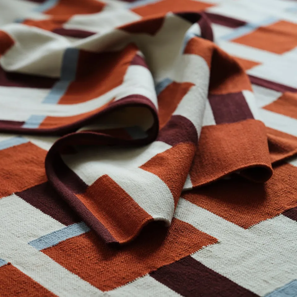 Textured wool rug with tight weave, vibrant orange and white geometric pattern. Soft, durable, handcrafted quality.