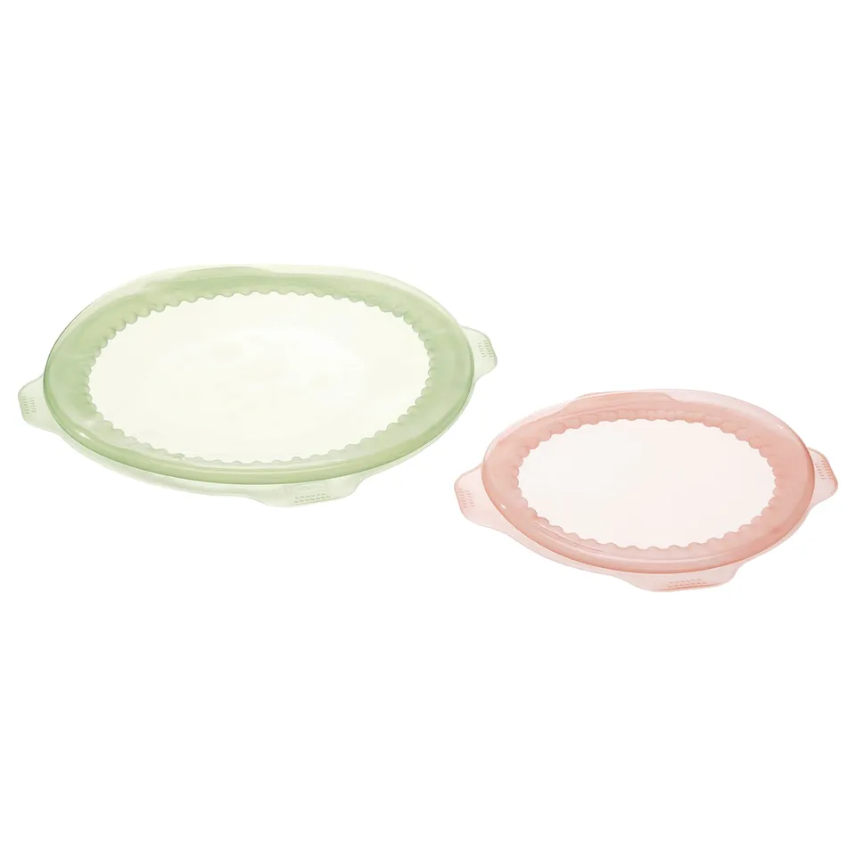 Two colourful silicone dish covers, one light green, one light pink, scalloped edge design, round shape.