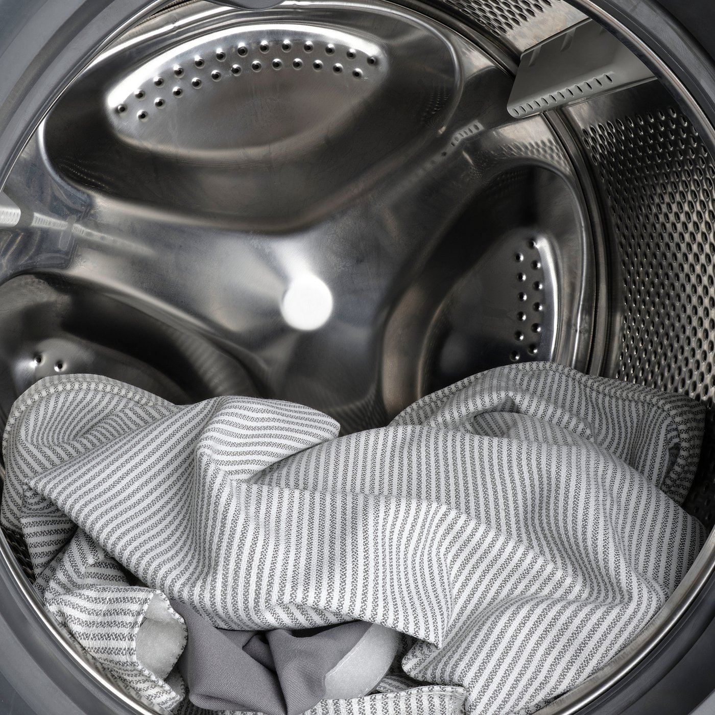 Washing machine drum with grey striped laundry, showing easy-to-clean feature.