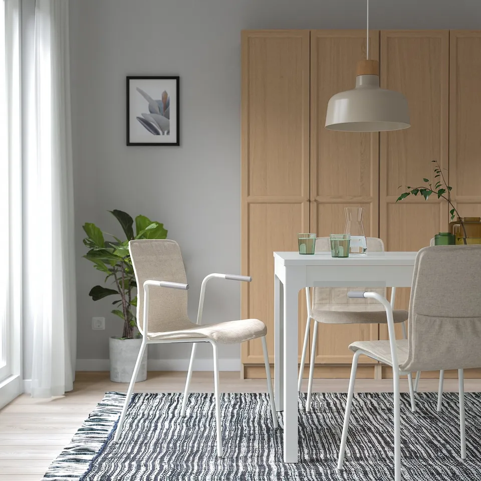 Modern dining room with LÄKTARE chair, cushion, wooden cabinets, rug, green glassware.