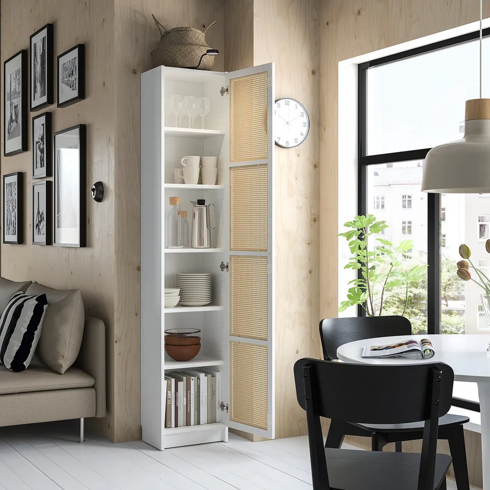 Modern living room with white BILLY bookcase, black dining chairs, sofa, wooden wall, and large window.