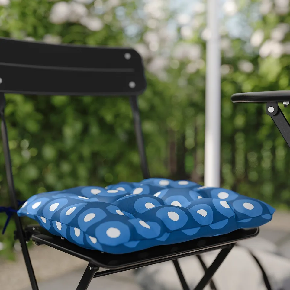 Blue geometric-patterned cushion on black foldable chair for outdoor use.