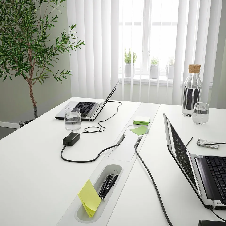 Modern office table with integrated power supply and clever cable management, featuring open co-working spaces and conference settings.