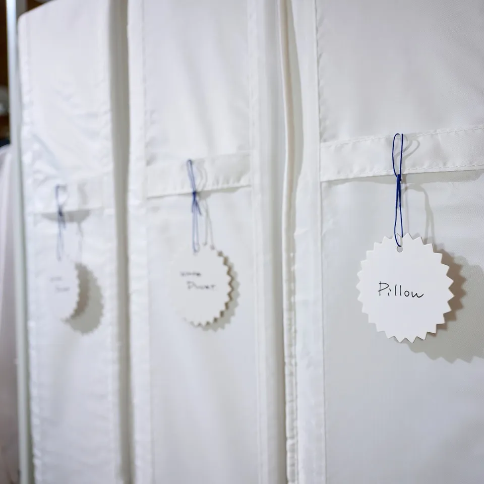 White labels on curtains; one with pillow text, another with duvet; blue strings tie tags.