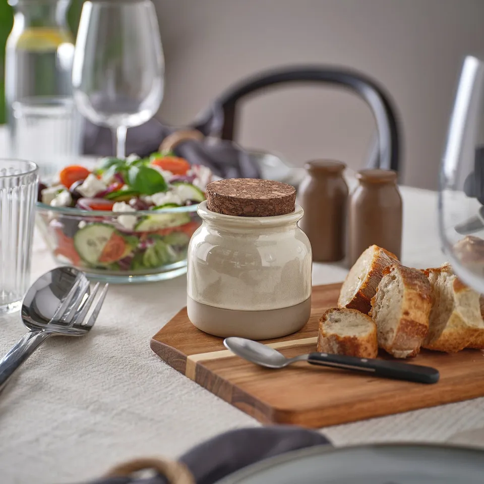 BRUGDHAJ jar, beige, stoneware, small, with cork lid, sits between salad bowl and bread. Holds condiments or spices.
