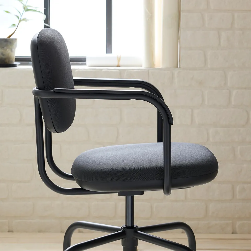 Modern office chair with sleek black frame, plush padding, and adjustable height, positioned against a white brick wall. Ideal for comfort and style.