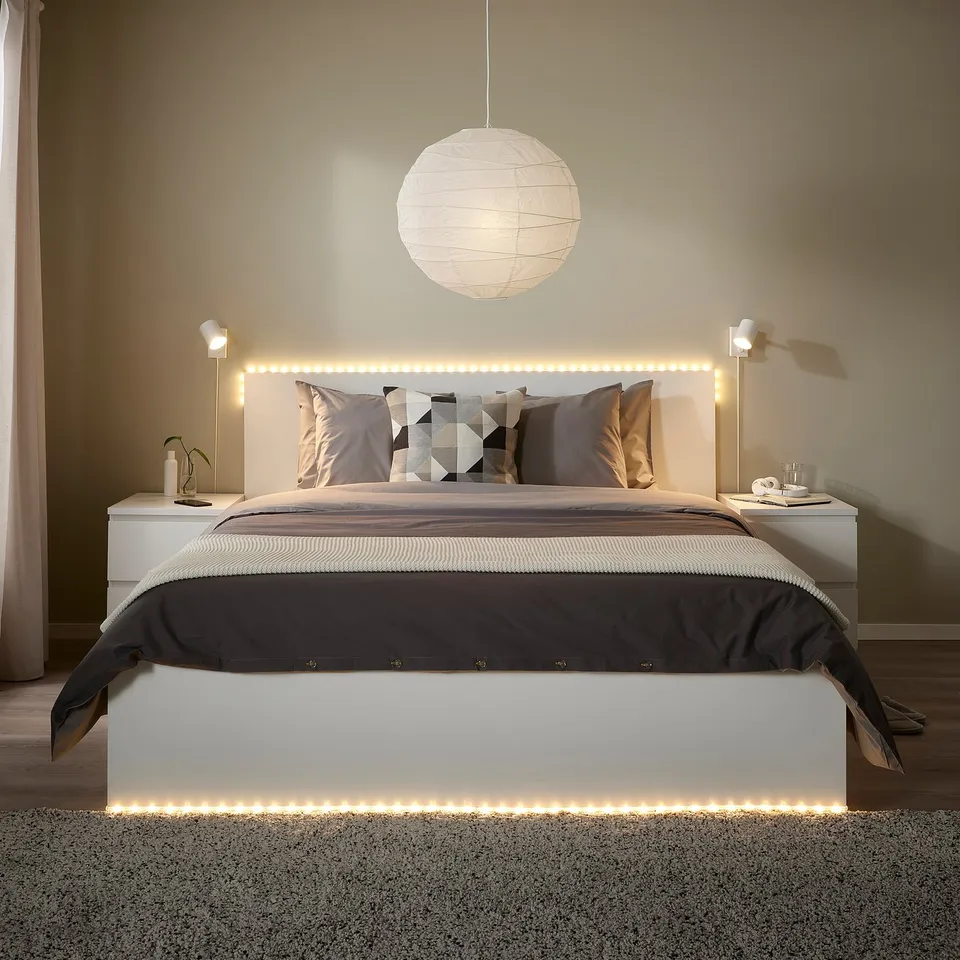 Modern bedroom with king-size bed, white ORMANÄS led lights, grey pillows, nightstands with lamps, and large hanging light.