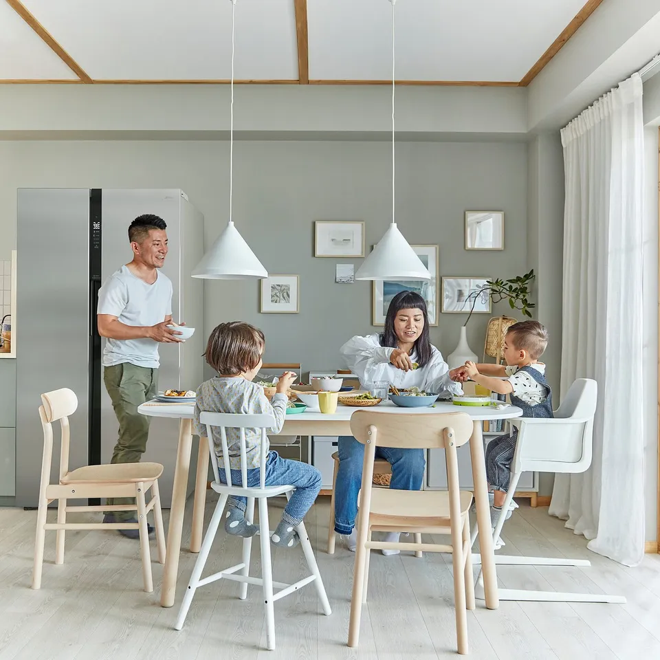 Family enjoys meal around modern dining table with AGAM junior chairs, white with beech, designed for children.