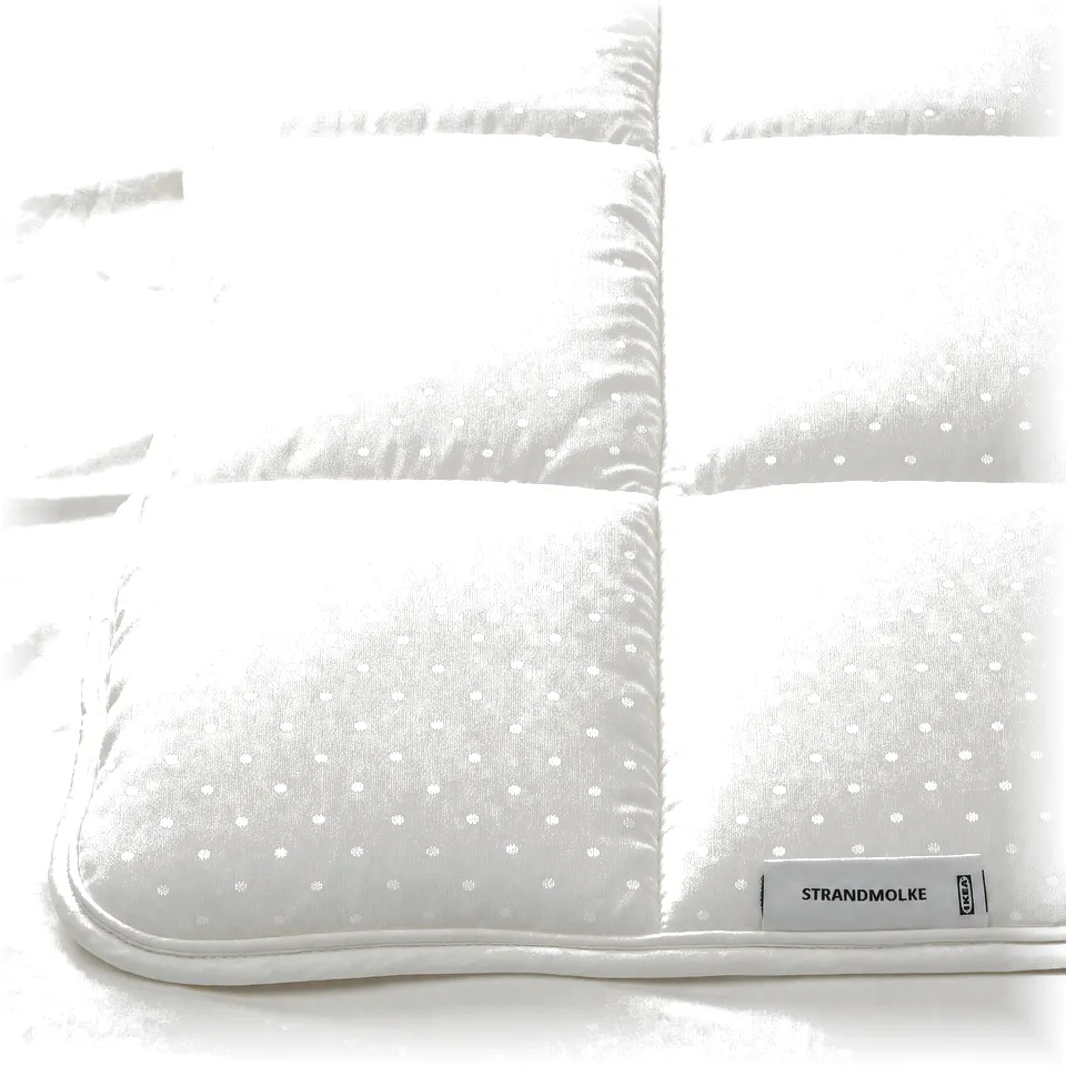 Fine, white duvet with subtle pattern on bed, labelled STRANDMOLKE.
