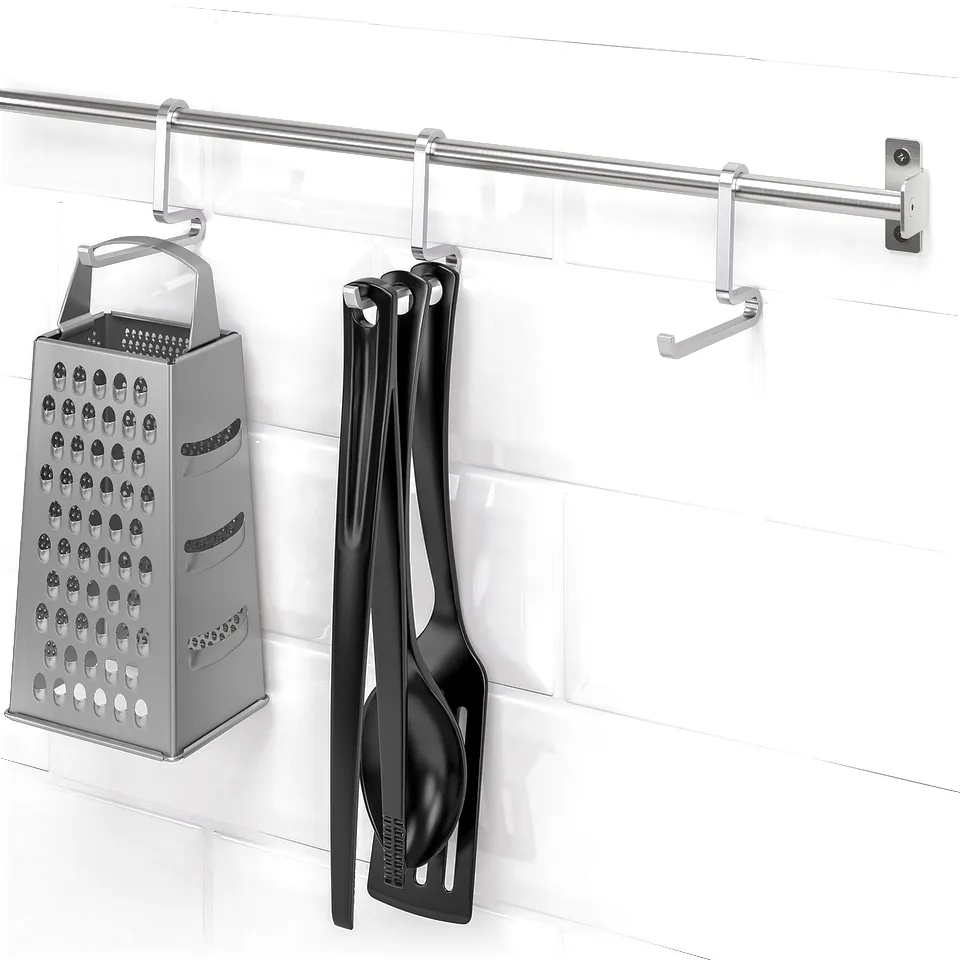Wall-mounted kitchen utensils: grater, tongs, and spoon. Efficient, space-saving storage.