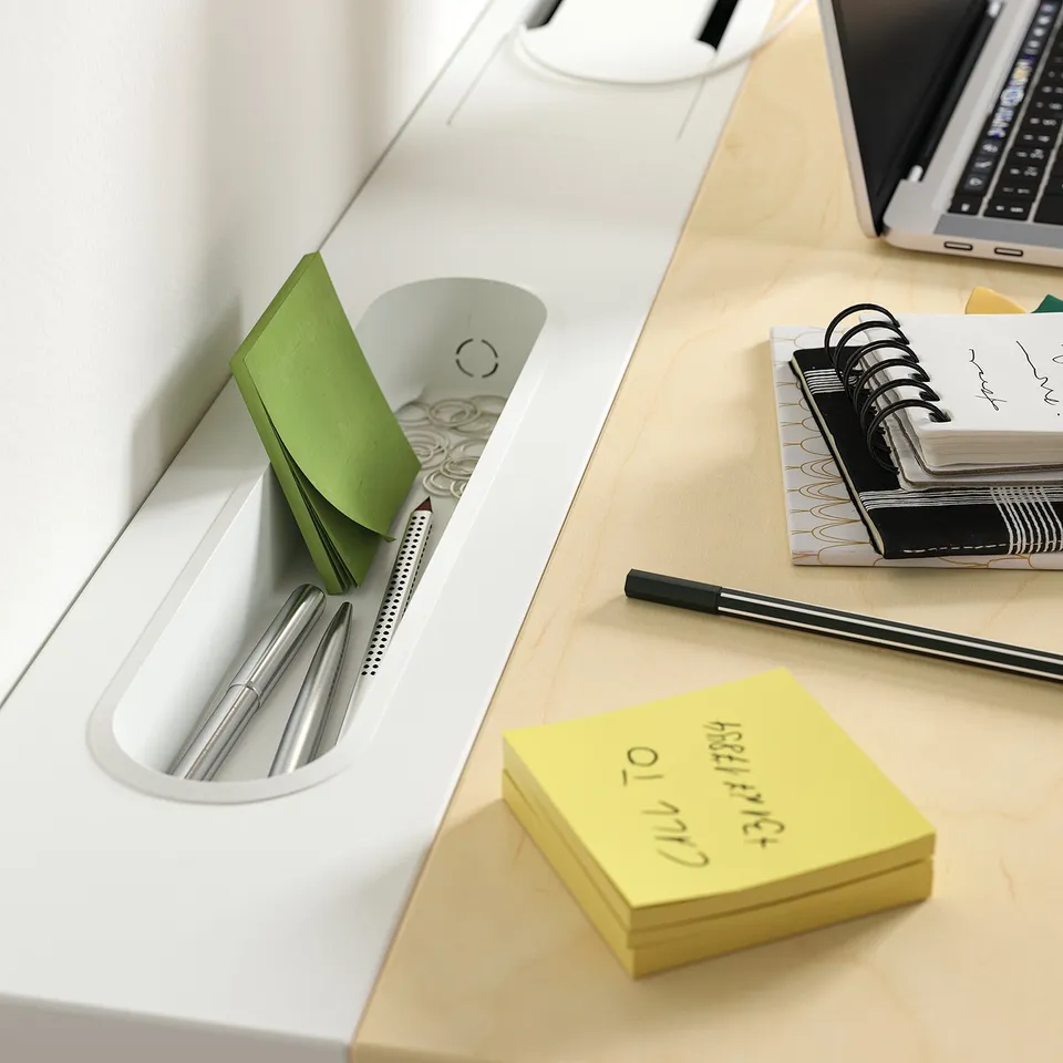 Organised work space: laptop, notepad, pens, and sticky notes on a wooden desk.