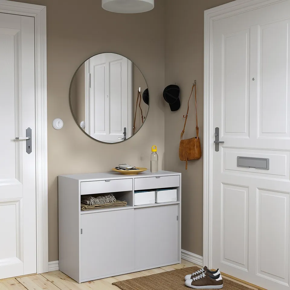 Grey SPIKSMED cabinet with sliding doors, corner placement with mirror and rug.