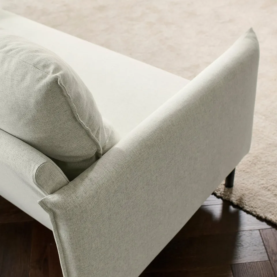 Modern sofa with high back, soft cushions. Light-colored fabric, sleek design, black legs. Comfortable and elegant.