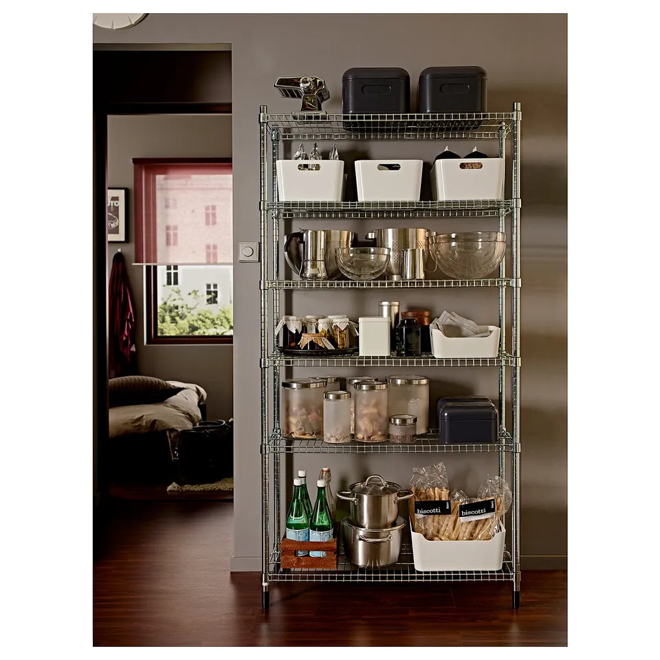 Metal storage rack with various kitchen items neatly organised, including bowls, jars, and containers, against a wall in a home setting.