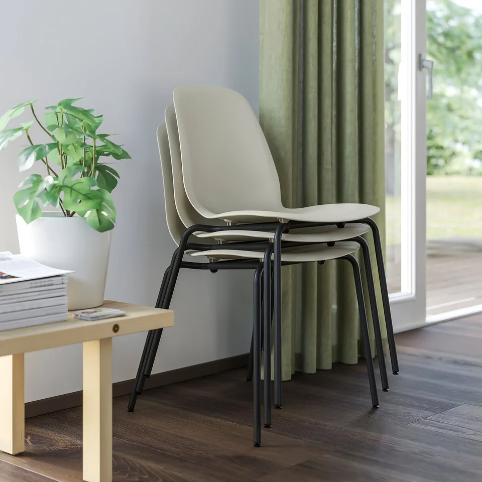 Stacked chairs, window with green curtains, books, plant.
