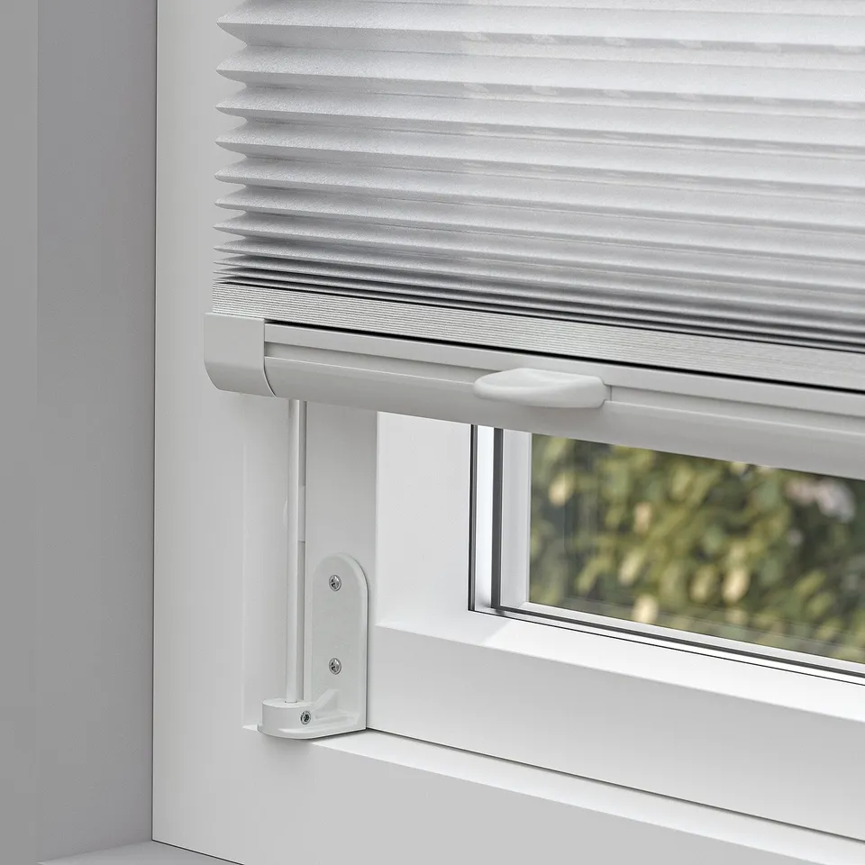 Close-up of pleated blind on window, showing cordless handles for adjusting privacy and light control.