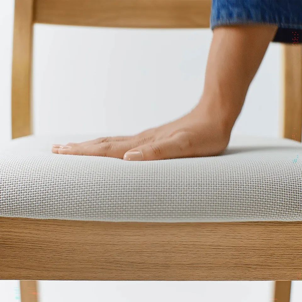A persons foot touches a soft, textured, off-white cushion atop a sturdy wooden table.