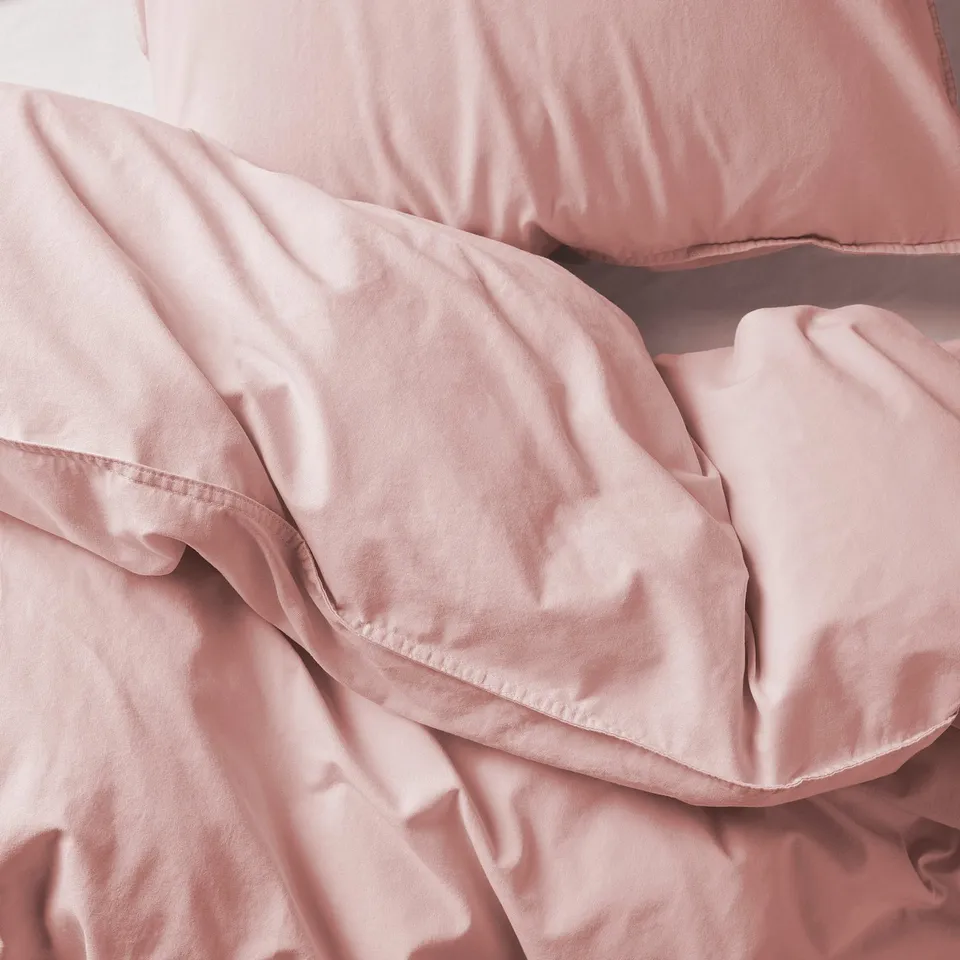 A close-up of a pink bedding set, appearing soft and cosy, made from smooth cotton fabric.