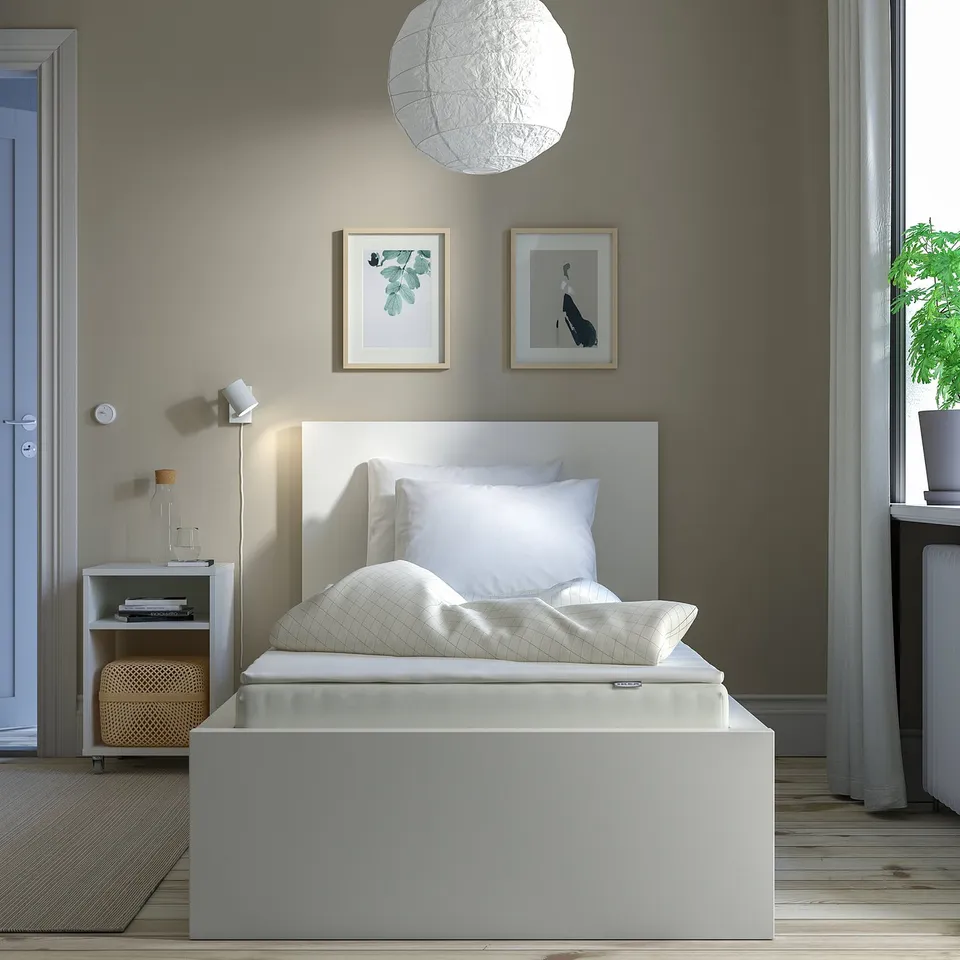 Modern bedroom with grey walls, white bed, lamp & art.