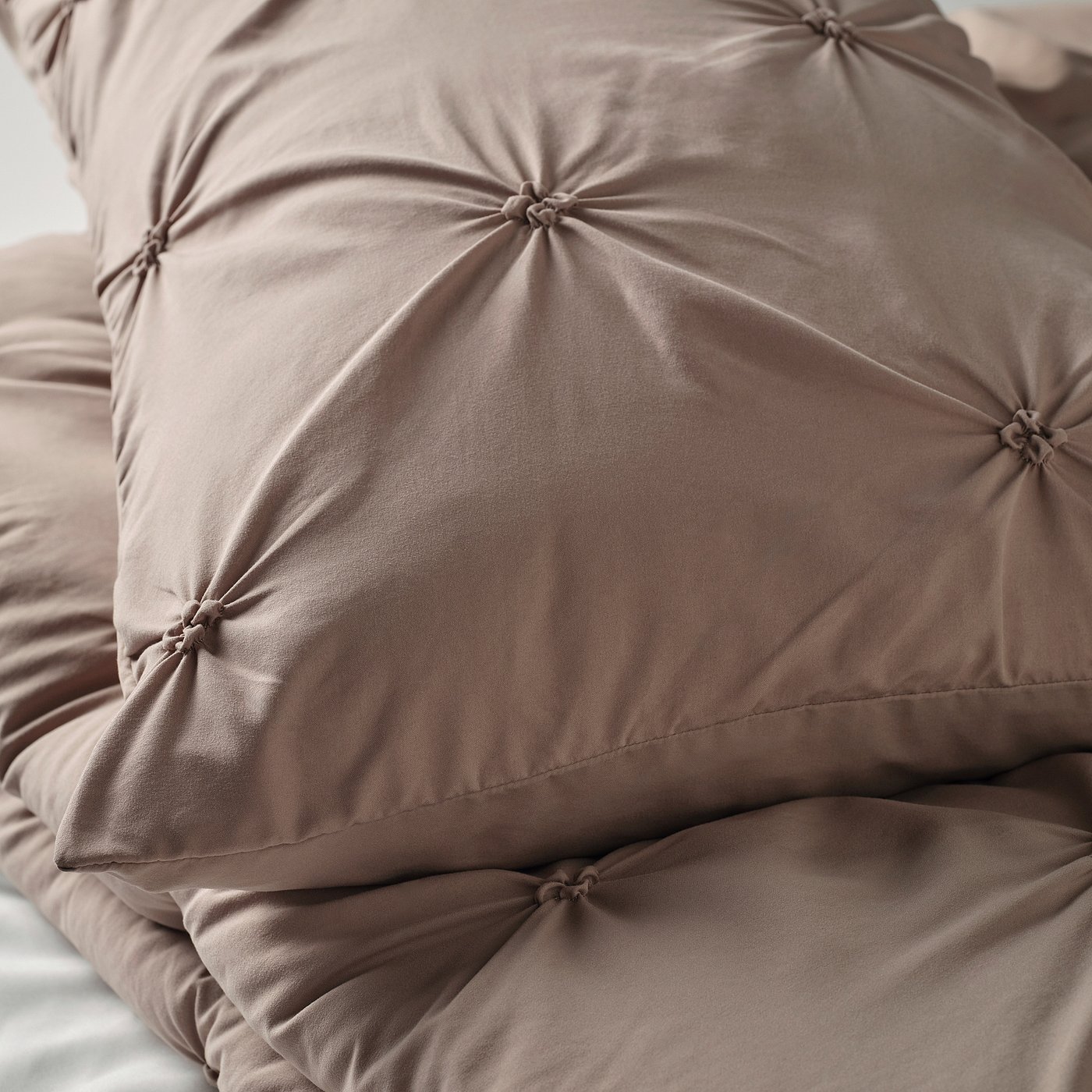 Close-up of a soft, textured brown comforter with intricate pintuck design, showcasing its cosy and inviting look.