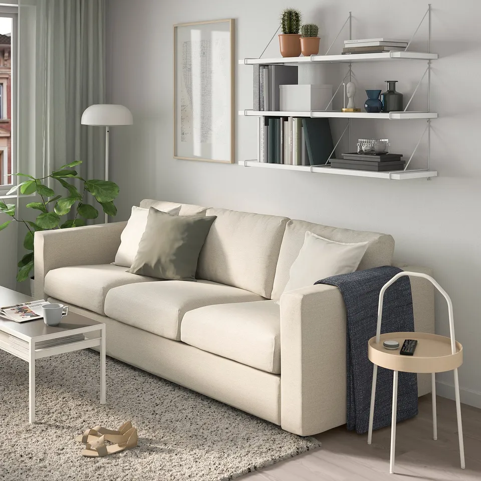 Modern living room with BERGSHULT shelf, beige sofa, plant, and lamps.