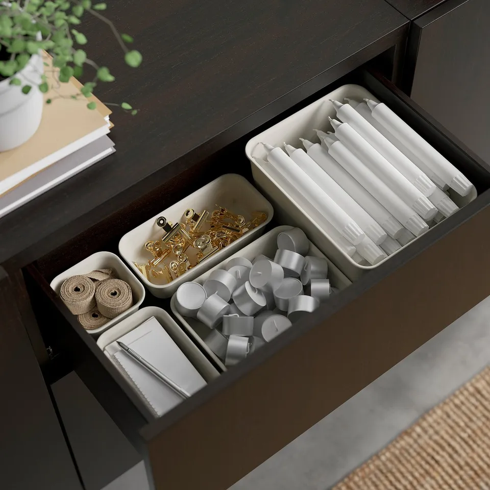 Open desk drawer showing organised compartments with ribbons, clips, and pens.
